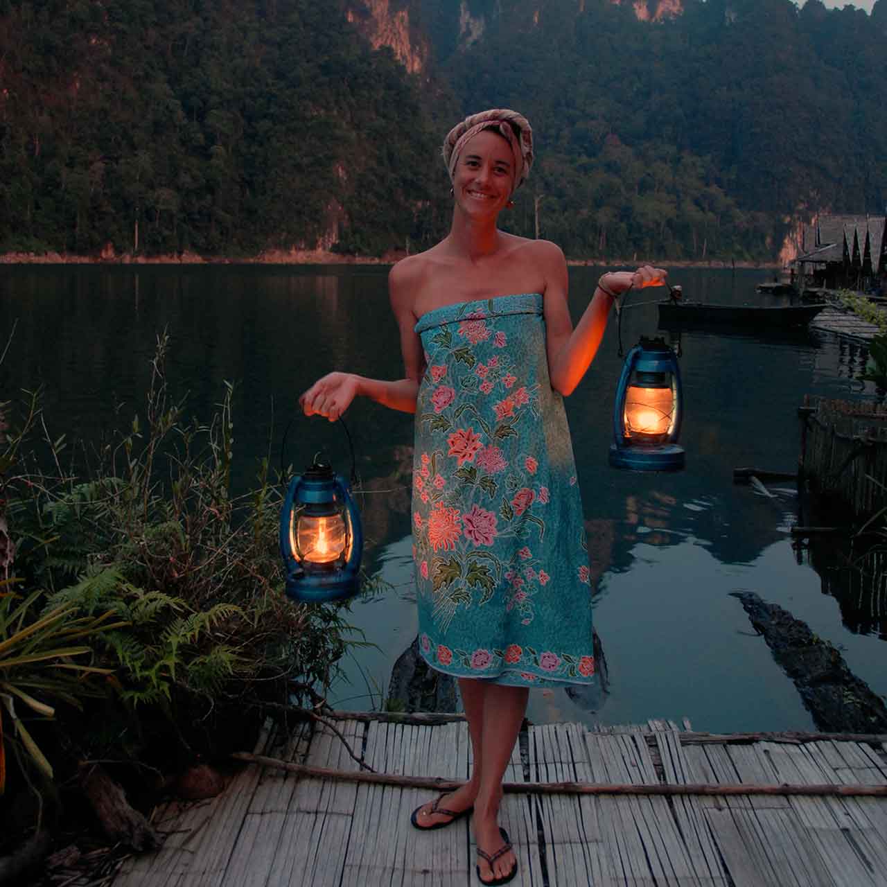 Woman standing on a pier holding lanterns on the lake at night