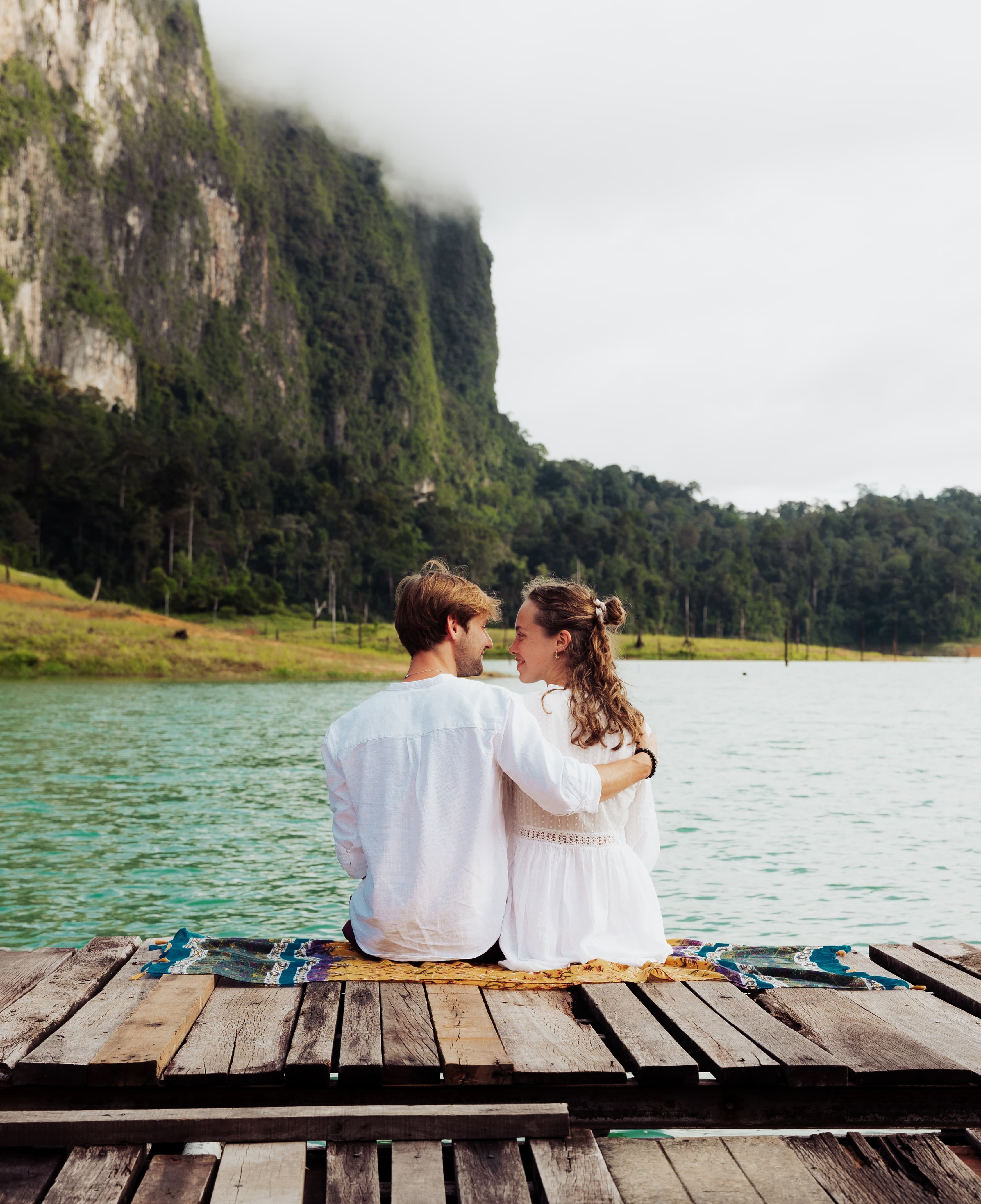 Couple sitting on wooden deck on Cheow Lan Lake